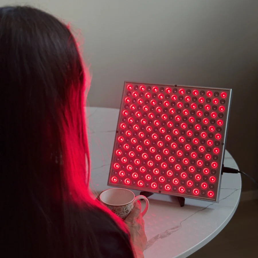 en kvinne drikker kaffe foran et rødtlys-panel